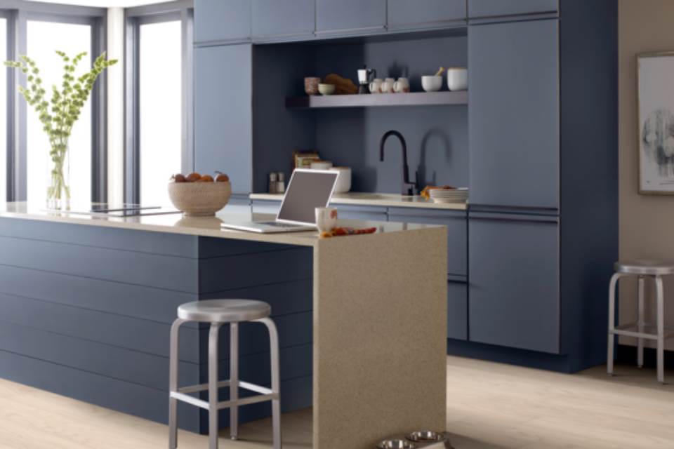 Slate blue cabinets and counter with metal accents and stone look countertop in kitchen.